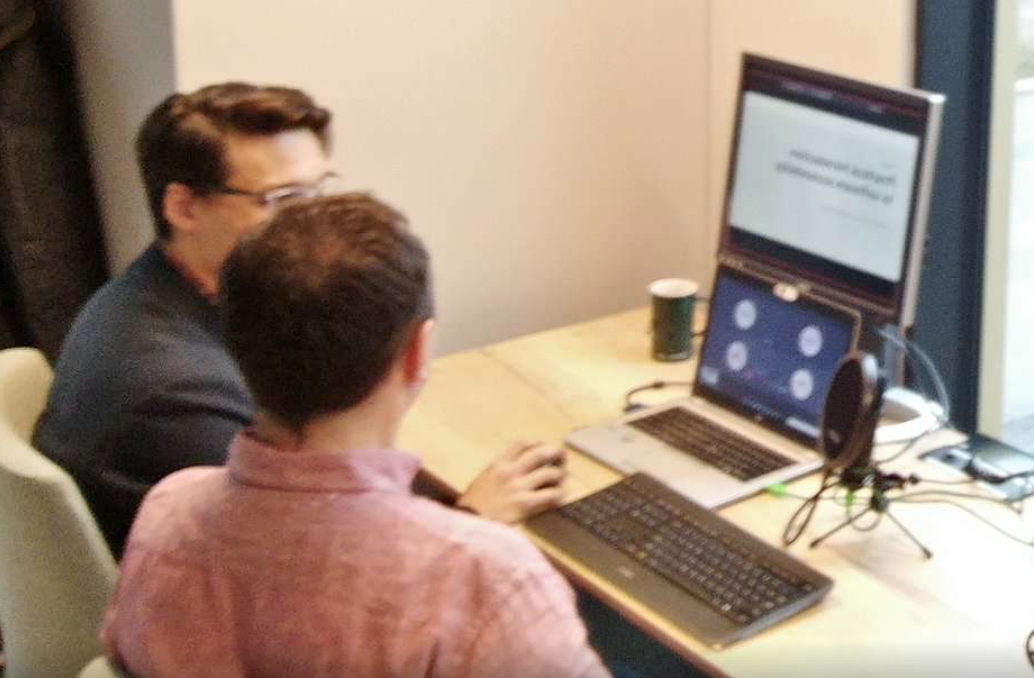 Picture of Dawid Górny and Kacper Mikocki sitting in front of screen and monitor while remote workshops.